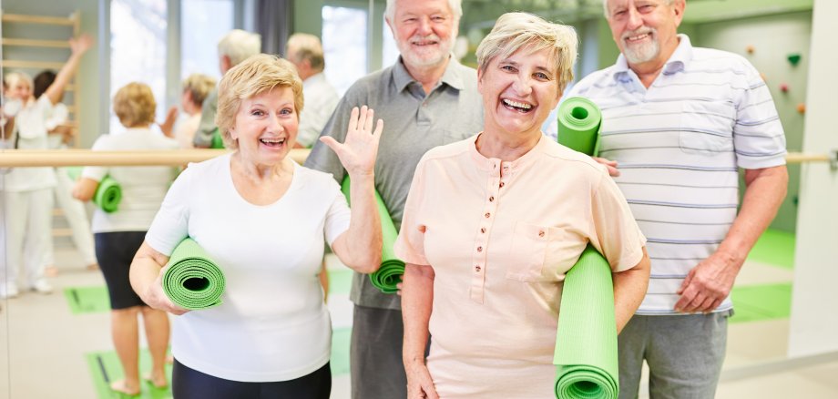 Glückliche Senioren mit Yogamatten im Sportstudio