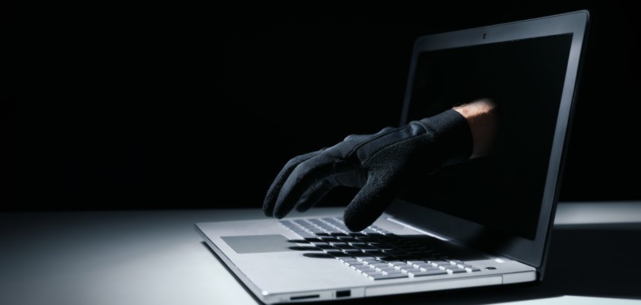 internet fraud and cyber attack concept. thief hand out of lapto