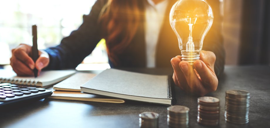 Businesswoman holding a lightbulb while taking note on notebook